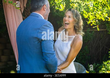 Homme tenant la femme en robe blanche, pressant et provoquant des coeurs animés flottant pour le mariage Banque D'Images