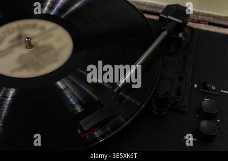 Gros plan, plan à grand angle d'une platine vinyle classique avec un disque vinyle noir tournant sur le plateau avec le tonearm et l'aiguille en regard Banque D'Images