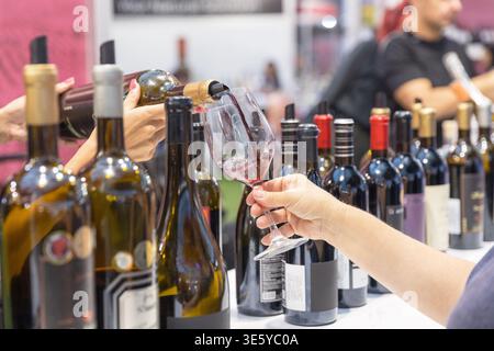 Dégustation de vin avec sommelier versant du vin rouge pour les invités à la cave ou à l'exposition de nourriture et de boissons Banque D'Images