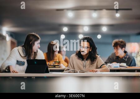Étudiants universitaires étudiant ensemble à une longue table dans un espace d'étude de campus moderne Banque D'Images