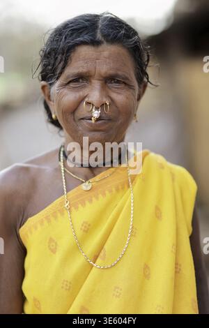 Odisha, Inde - 26 mars 2026 : vue d'une femme indigène ornée d'un saree jaune vif et d'un anneau de nez traditionnel, son visage altéré racontant tal Banque D'Images