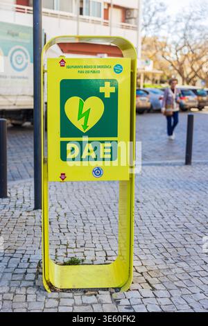 FARO, PORTUGAL - MARS 30 2026 - unité de défibrillateur DAE jaune vif dans une rue pavée, équipement de sauvetage pour un usage public. Jaune vif DAE Defi Banque D'Images