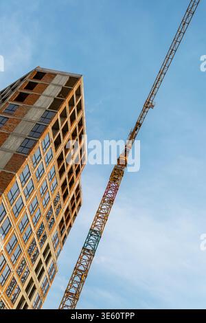 Construction de bâtiments à faible angle et grue à tour. Vue en angle bas d'un immeuble de grande hauteur en construction avec une grue à tour contre le ciel bleu Banque D'Images