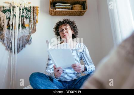 Belle femme intelligente dans son livre de lecture des années 40 angle bas à la maison Banque D'Images