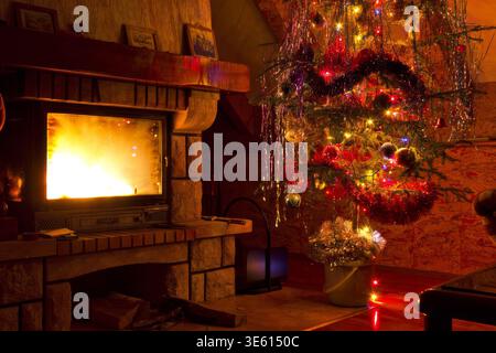 Arbre de Noël avec cheminée brûlant dans le salon confortable, ambiance festive de vacances d'hiver Banque D'Images