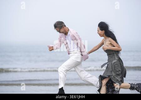 En juin 2025, un homme et une femme coréens dans la cinquantaine courent à pleine vitesse le long du littoral accidenté rempli de rochers déchiquetés et de crashs Banque D'Images