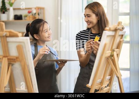 Une mère et sa fille expérimentent la créativité ensemble tout en peignant, profitant de moments de qualité en famille remplis de sourires et de joie Banque D'Images
