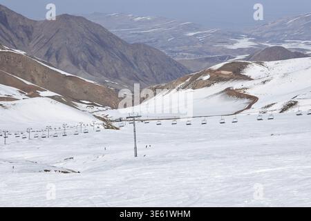 Téléphérique, skilift à la station de ski d'hiver, vue de loin. Pente enneigée de piste de snowboard et pentes sud sans neige de hautes montagnes. Pays naturel c Banque D'Images