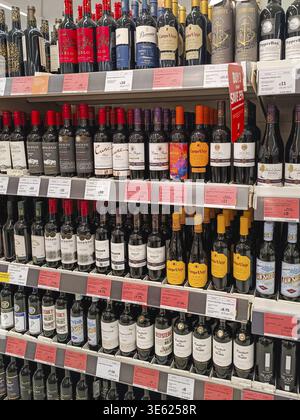 Une allée de supermarché bien approvisionnée avec des rangées de bouteilles de vin rouge et blanc assorties soigneusement disposées sur les étagères du magasin pour les clients de détail. Londres, Banque D'Images