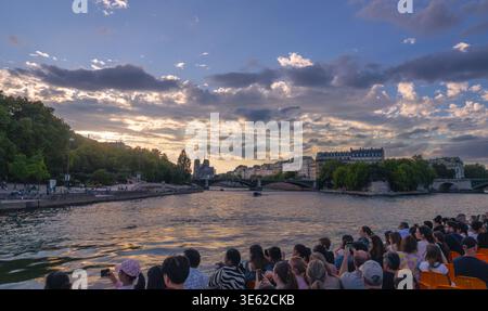 Paris, France - 08 04 2025 : un grand plan panoramique depuis le pont d'un bateau de tourisme sur la Seine. L'image capture le coucher de soleil éclatant reflétant sur th Banque D'Images