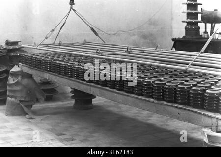 Slavyansk, années 1970, usine d'armature-isolant. Les isolateurs en céramique finis OFR-750 sont disposés en rangées nettes sur une longue table de production industrielle. Le processus technologique de séchage ou de refroidissement des produits à l'intérieur de l'atelier d'entreprise. L'atmosphère industrielle d'une grande usine soviétique, démontrant l'ampleur impressionnante de la fabrication d'équipements électriques. Une authentique photographie d'archives historiques véhiculant l'esprit du travail créatif, la vie quotidienne industrielle soviétique, les jours de travail de routine de l'époque, et le Donbass paisible. Banque D'Images
