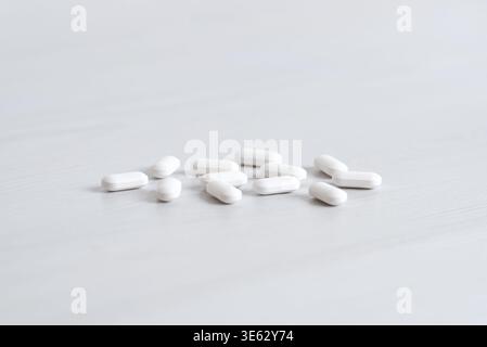 Pilules blanches dispersées sur la surface avec une faible profondeur de champ, concept médical et pharmaceutique Banque D'Images