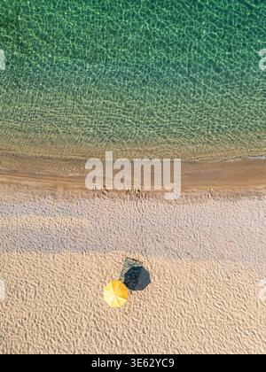 Vue aérienne de haut en bas d'un parasol jaune sur une plage vide de sable blanc Banque D'Images