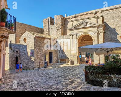 Une place pavée ensoleillée dans la ville historique de colline d'Erice, Sicile, Italie, avec le grand portail voûté de la Chiesa Madre (église mère) Banque D'Images