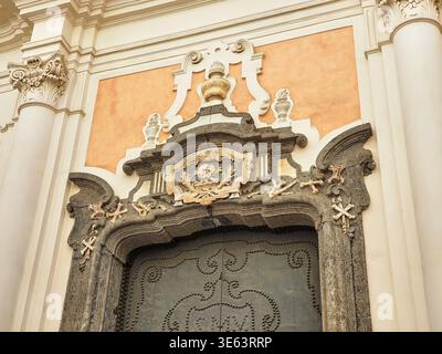 Vue détaillée d'une entrée d'église baroque ornée d'une arche en pierre volcanique sombre ornée d'éléments décoratifs macabres, dont des sculptures Banque D'Images