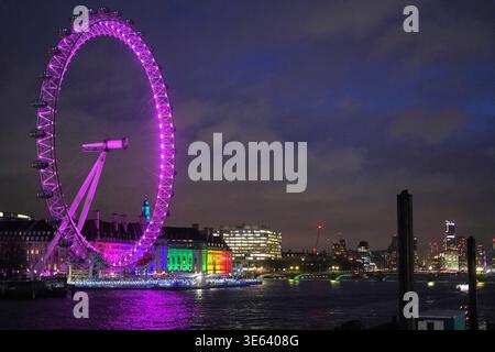 Vue nocturne du London Eye, une grande roue géante sur la rive sud de la Tamise à Londres, illuminée de vives lumières violettes et magenta. Banque D'Images