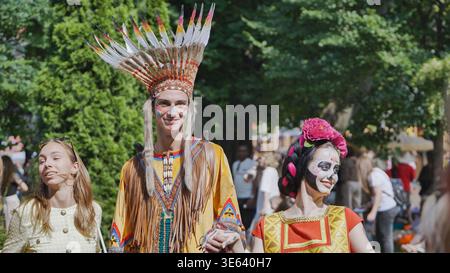 Moscou, Russie - 5 juillet 2025 : jeune homme dans un bonnet de guerre et une femme avec un crâne de sucre maquillage lors d'un festival en plein air Banque D'Images
