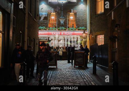 Vue nocturne du pub historique Lamb & Flag situé sur Rose Street à Londres, Royaume-Uni. L'image capture une ruelle pavée étroite Banque D'Images