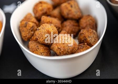 Délicieuses boulettes de falafel frites brunes dorées ou salées servies dans un bol en céramique blanc propre sur une surface sombre, soulignant la texture croustillante Banque D'Images