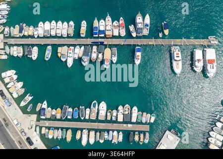 Vue aérienne du port de plaisance de Mgarr à Gajnsielem, Gozo, montrant des jetées parallèles avec des bateaux amarrés et une mer turquoise chatoyante. Banque D'Images