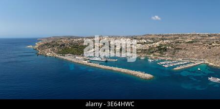 Vue aérienne du port de Mgarr sur Gozo avec Gozo Fast Ferry au terminal, quais de marina, brise-lames et ville côtière sous ciel clair d'été. Banque D'Images