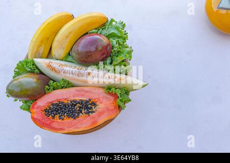 Assortiment de fruits tropicaux avec melon de papaye, bananes mangue et laitue sur assiette vue de dessus composition Banque D'Images
