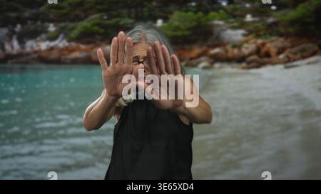 Femme avec les paumes dehors arrêt geste sur la plage tenant les mains levées près de la caméra ; alarme de limite personnelle. Banque D'Images
