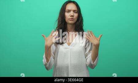 Femme avec les paumes ouvertes levées vers la caméra dans un cadre de studio montrant un geste expressif de la main ; introspection calme. Banque D'Images