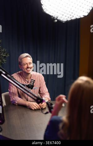 Annonceur masculin souriant enregistrant un podcast audio pendant une session de diffusion en direct Banque D'Images