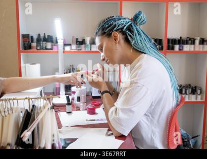 Du haut de la récolte méconnaissable manucure faisant nail art pour la cliente féminine dans le salon de beauté Banque D'Images