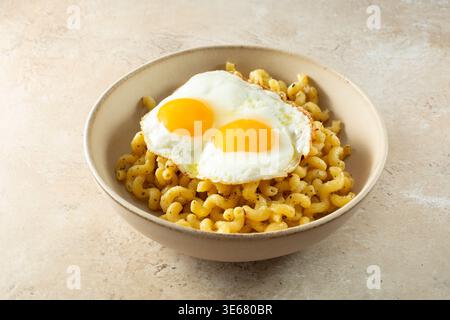 Vue sur un bol de cavatappi aglio e olio sans gluten et sans produits laitiers, garni d'œufs au plat. Banque D'Images