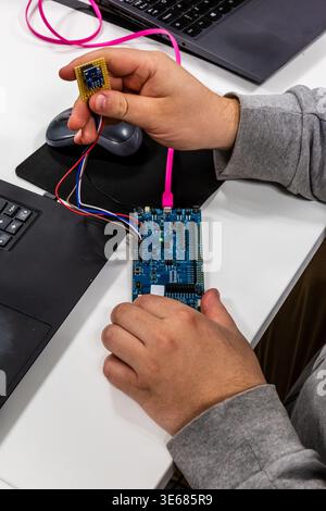 main tenant une carte électronique qui est connectée à une autre carte avec un fil Banque D'Images