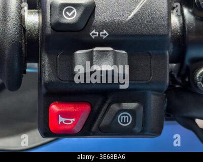 Gros plan détaillé d'un ensemble de commande de guidon de moto avec un bouton d'avertisseur sonore rouge, un commutateur de clignotant et un sélecteur de mode. Parfait pour le maintenan de vélo Banque D'Images