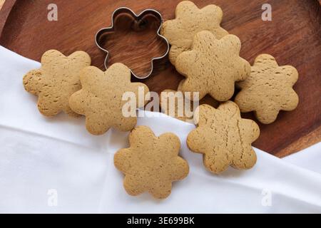 Gros plan de biscuits dorés faits maison disposés sur une surface en bois. Les tons chauds et la lumière naturelle créent une atmosphère chaleureuse de cuisson Banque D'Images