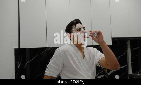 Homme avec de la crème à raser sur le visage regardant un téléphone Banque D'Images