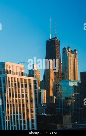 La vue montre de grands bâtiments de Chicago sous un ciel bleu clair tandis que le soleil frappe les structures en verre et en béton. La scène capture le paysage urbain Banque D'Images