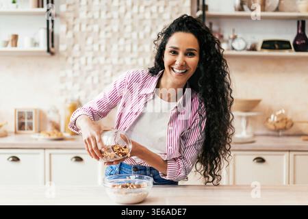 Femme prépare une collation saine dans une cuisine moderne tout en souriant joyeusement Banque D'Images