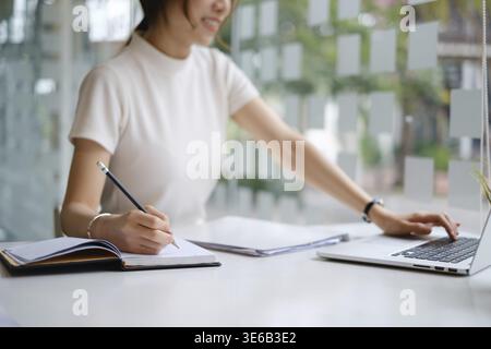 Jeune femme à l'université de prendre des notes et d'utiliser le surligneur. Étudiant ciblé dans une salle de classe en ligne. Concept d'éducation authentique Banque D'Images