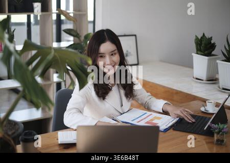 Portrait de secrétaire asiatique occupé souriant et attendant le client tout en travaillant au bureau. Concept Business Finance Banque D'Images