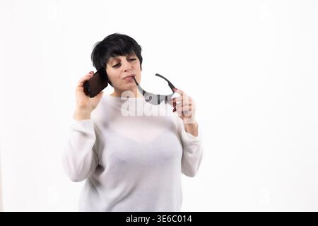 Femme avec les cheveux courts tenant des lunettes et regardant réfléchi Banque D'Images