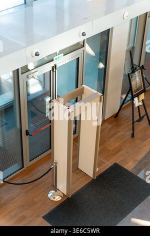 Entrée de bâtiment moderne dotée de portes vitrées, de barrières de sécurité pour détecteurs de métaux et d'un salon élégant dans le hall. Prise de vue en grand angle d'un mépris lumineux Banque D'Images