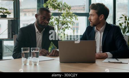 Réunion professionnelle d'équipe d'affaires dans le bureau de deux hommes d'affaires multiraciaux hommes d'affaires caucasien homme patron PDG de la société parlant avec l'agent afro-américain Banque D'Images