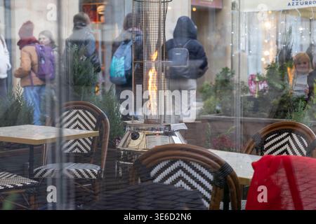 Vue intérieure de la salle à manger extérieure du café urbain, avec chauffage de patio chaud, sièges confortables, et des reflets de verre de l'activité de la rue, suggérant cool nous Banque D'Images