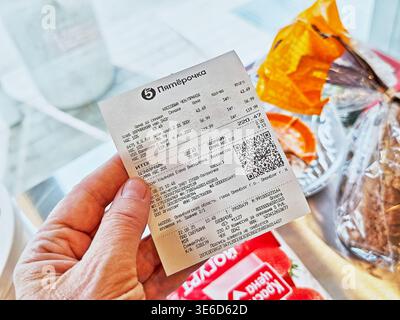 Orenburg, Russie - 22 août 2025 : une personne détient un reçu de magasin indiquant les articles achetés et les dépenses totales d'une récente visite d'épicerie. Banque D'Images