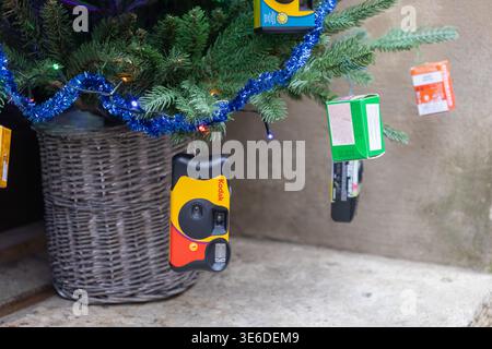 Cracovie, Pologne - 1er décembre 2025 : gros plan montrant un appareil photo jetable Kodak vibrant comme ornement nostalgique sur un sapin de Noël vert festif, décorat Banque D'Images
