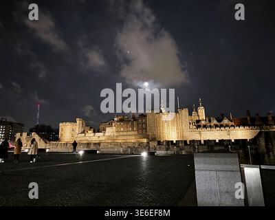 Vue au clair de lune de la Tour de Londres brillante contre les nuages avec les visiteurs sur le parvis la nuit. Banque D'Images