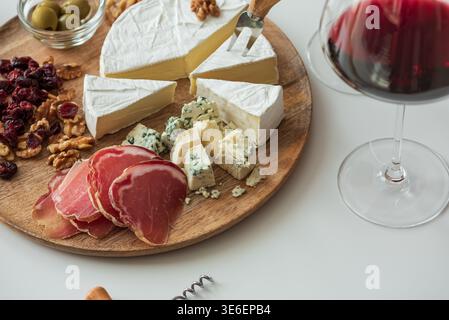 Composition élégante de carton de charcuterie comprenant un assortiment de fromages, charcuteries, noix, canneberges séchées, gressins, olives, et gelée rouge, jumelées Banque D'Images