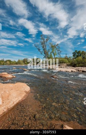 Les eaux peu profondes de la rivière American coulent sur des pierres lisses et des bancs d'argile Banque D'Images