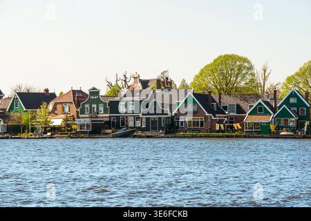 Vue panoramique sur les maisons hollandaises traditionnelles et les toits à pignons le long d'un front de mer calme près d'Amsterdam, en Europe, avec des arbres printaniers, un ciel bleu et serein Banque D'Images
