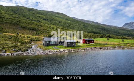 Vue pittoresque sur les cabanes de Ramsjøhytta sur les rives d'un lac en Norvège. La photo montre des cabanes en bois rouge et foncé nichées dans le m scandinave vert Banque D'Images